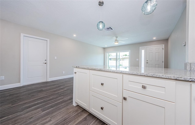 kitchen with pendant lighting, ceiling fan, white cabinetry, dark hardwood / wood-style floors, and light stone countertops