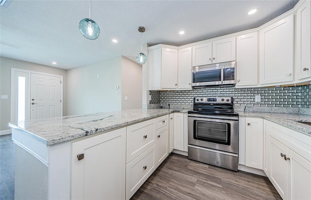 kitchen with appliances with stainless steel finishes, hanging light fixtures, white cabinets, and kitchen peninsula