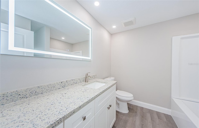 bathroom featuring wood-type flooring, toilet, and vanity