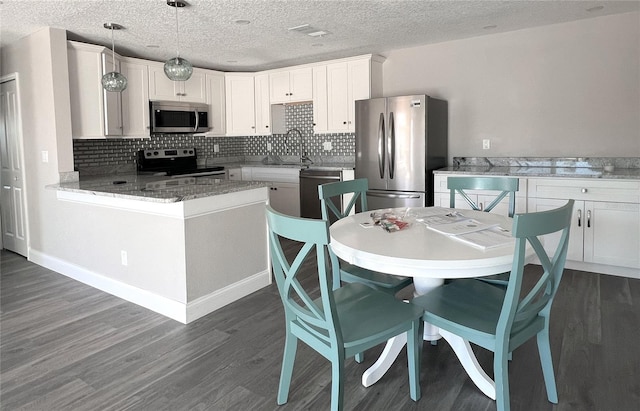 kitchen with white cabinets, stainless steel appliances, sink, decorative light fixtures, and backsplash