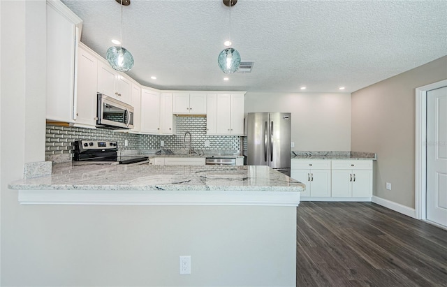 kitchen featuring appliances with stainless steel finishes, white cabinetry, light stone countertops, decorative light fixtures, and kitchen peninsula