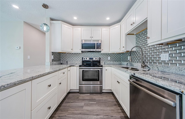 kitchen with sink, hanging light fixtures, dark hardwood / wood-style floors, stainless steel appliances, and light stone countertops