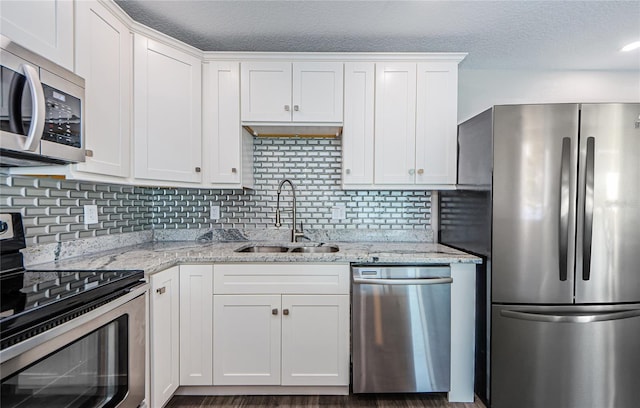 kitchen with sink, backsplash, white cabinets, light stone counters, and stainless steel appliances