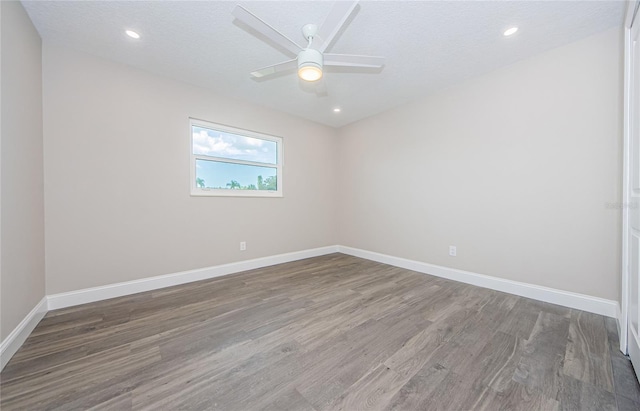 empty room with ceiling fan, wood-type flooring, and a textured ceiling