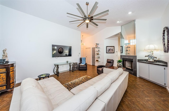 living room with a textured ceiling, a tile fireplace, ceiling fan, and vaulted ceiling