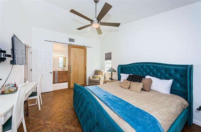 bedroom with a barn door, ceiling fan, lofted ceiling, and connected bathroom