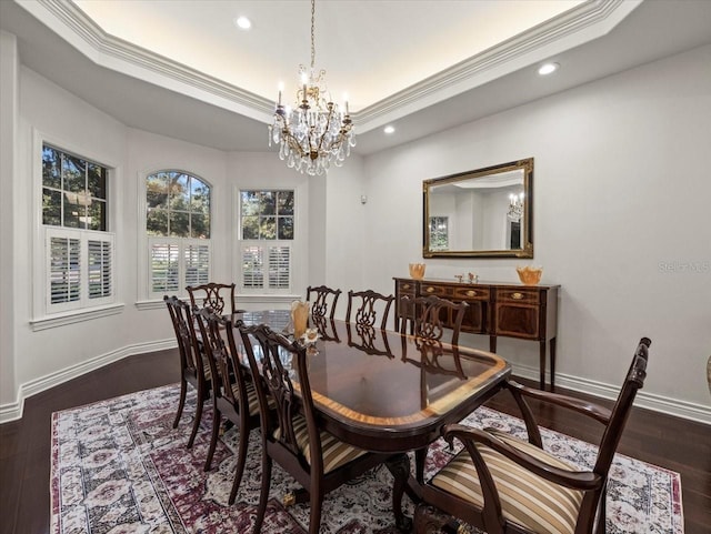 dining space with crown molding, a raised ceiling, dark wood-type flooring, and a chandelier