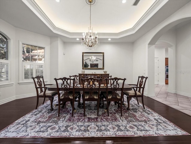 dining room with a chandelier, hardwood / wood-style floors, a tray ceiling, and crown molding