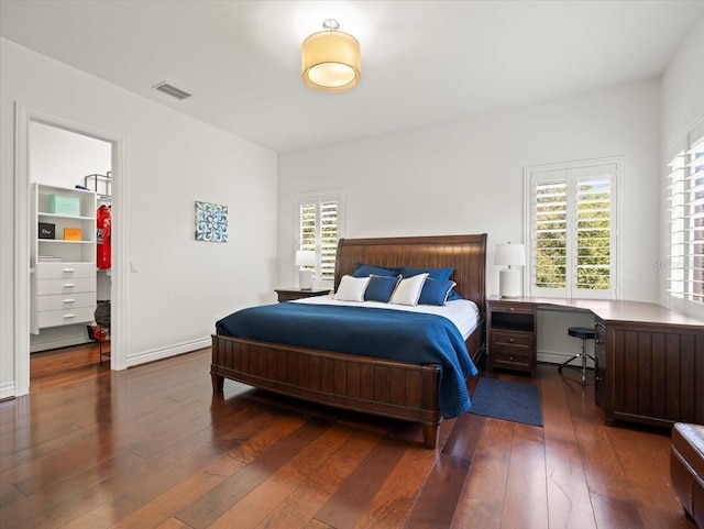 bedroom with a walk in closet and dark wood-type flooring