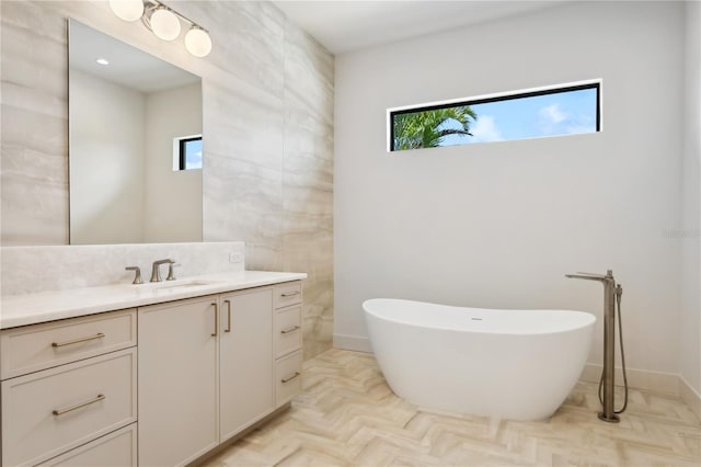 bathroom with backsplash, a freestanding bath, and vanity