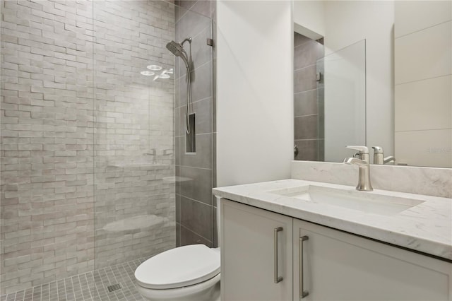 bathroom with tiled shower, vanity, and toilet