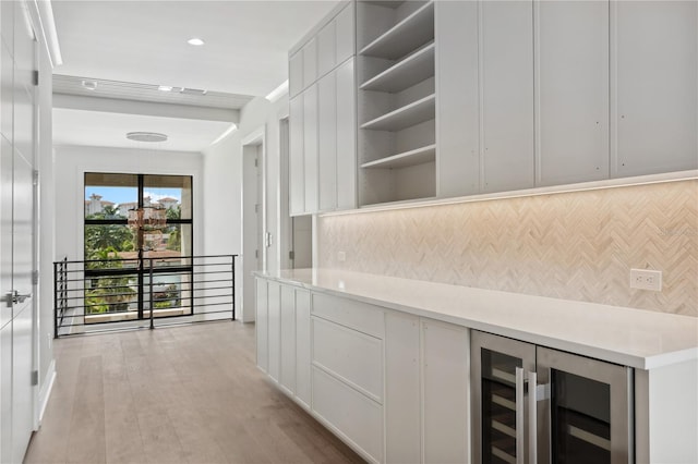 bar featuring light hardwood / wood-style flooring, wine cooler, backsplash, and white cabinetry