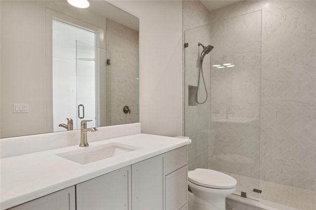 bathroom with toilet, tiled shower, and vanity