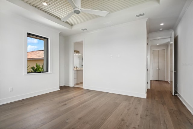 spare room with baseboards, visible vents, ceiling fan, wood finished floors, and crown molding