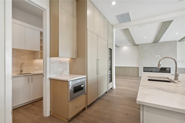 kitchen featuring sink, oven, backsplash, and light hardwood / wood-style floors