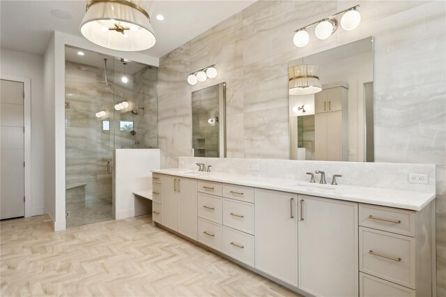 bathroom with a shower with shower door, vanity, and tile walls