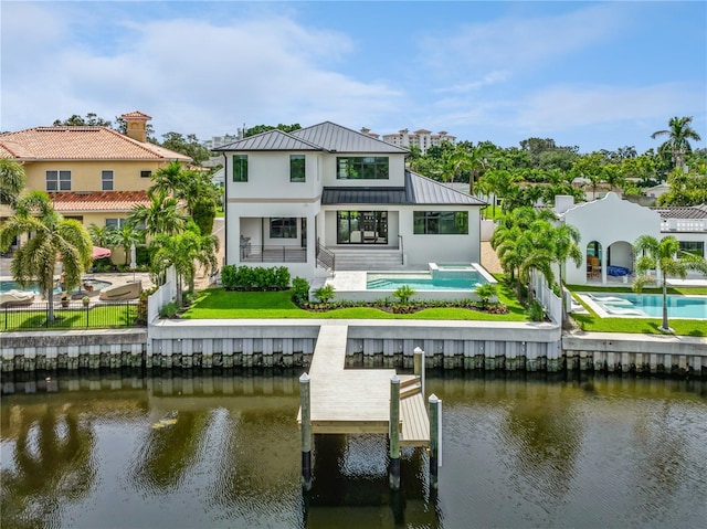 back of house featuring a water view, a standing seam roof, a fenced backyard, and metal roof