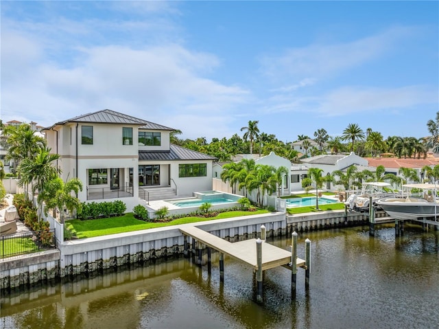 rear view of property with a water view, a standing seam roof, fence, and metal roof