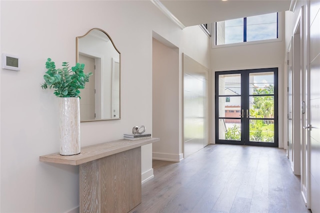 entrance foyer with french doors, baseboards, wood finished floors, and crown molding