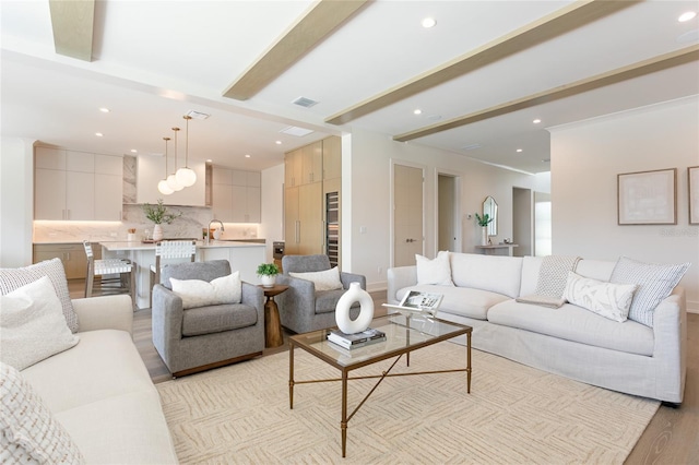 living area featuring visible vents, baseboards, light wood-style flooring, recessed lighting, and beamed ceiling