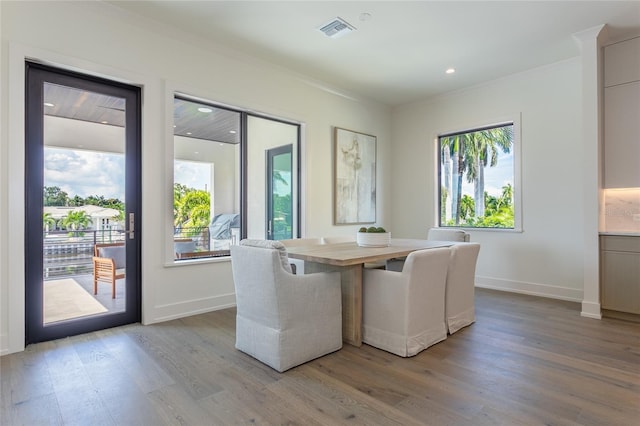 unfurnished dining area featuring crown molding, light wood-style floors, baseboards, and visible vents