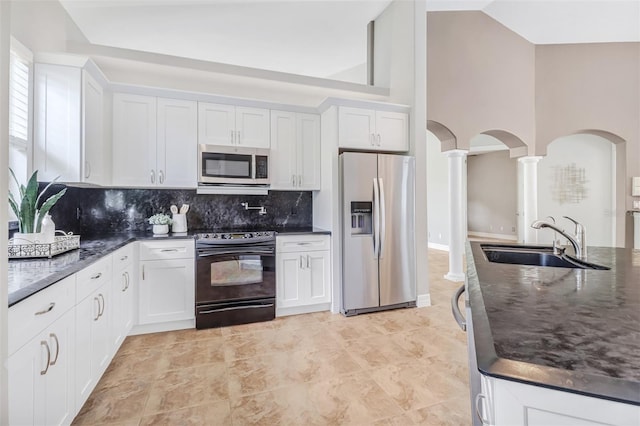 kitchen featuring decorative columns, stainless steel appliances, high vaulted ceiling, sink, and light tile floors