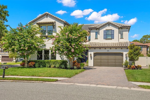 mediterranean / spanish home featuring a garage and a front yard