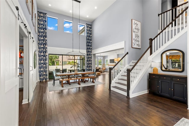 dining room with a towering ceiling, a barn door, and dark wood-type flooring