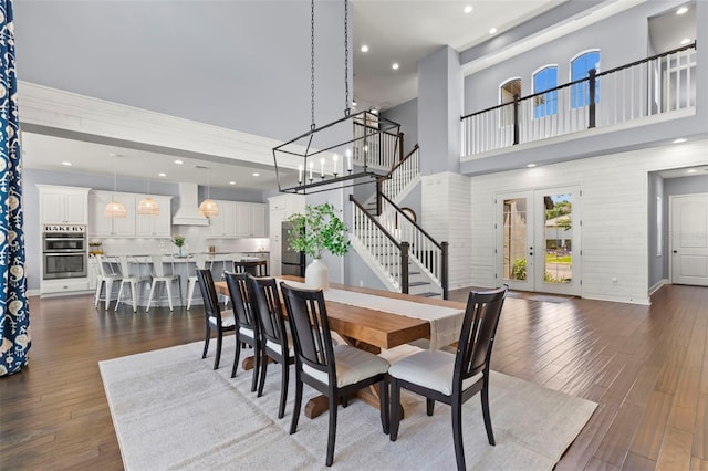 dining room featuring french doors, dark hardwood / wood-style flooring, a high ceiling, and a notable chandelier