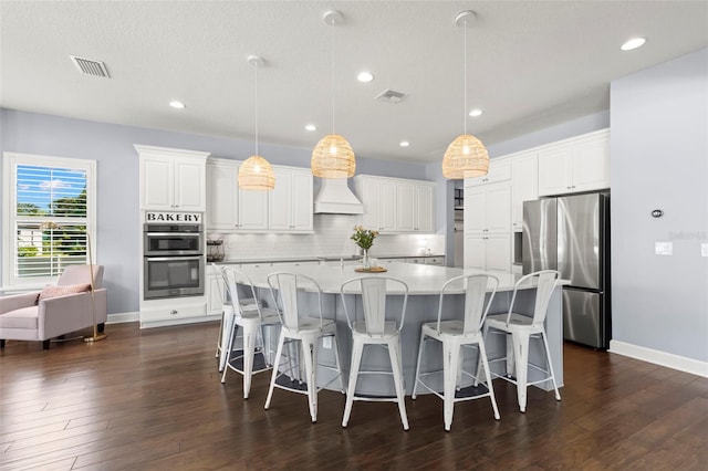 kitchen featuring white cabinets, a spacious island, custom range hood, and stainless steel appliances