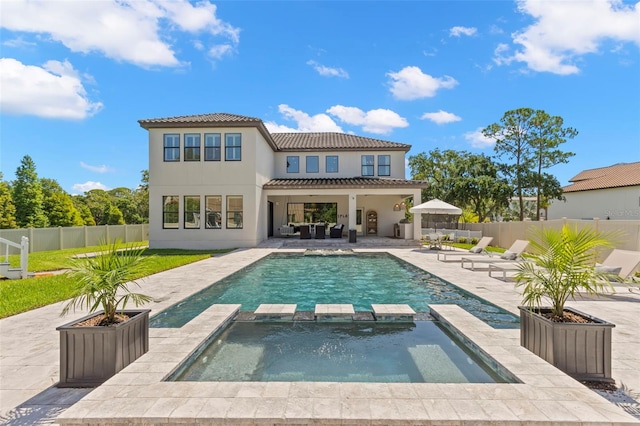 back of house with outdoor lounge area, a patio, and a pool with hot tub