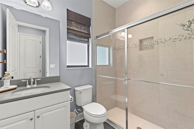 bathroom featuring vanity, a shower with shower door, and toilet