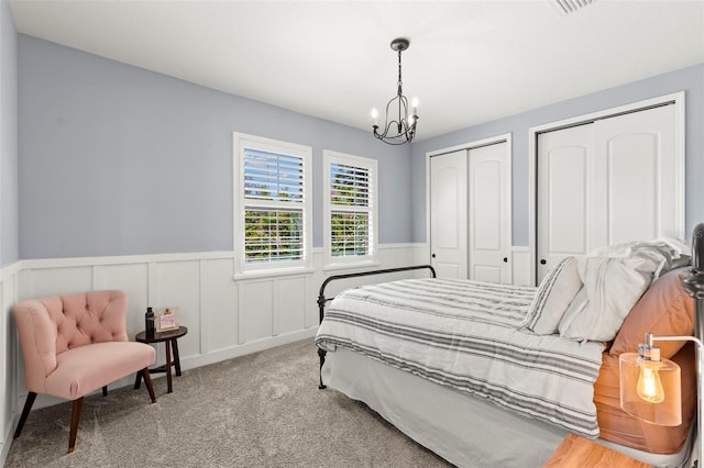 bedroom with light carpet, two closets, and a notable chandelier