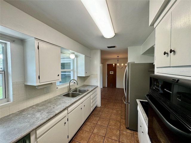 kitchen with black oven, white cabinetry, plenty of natural light, and sink