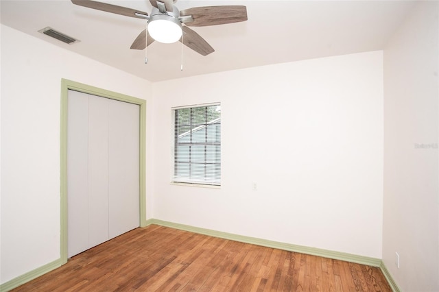 unfurnished bedroom with ceiling fan, a closet, and hardwood / wood-style flooring