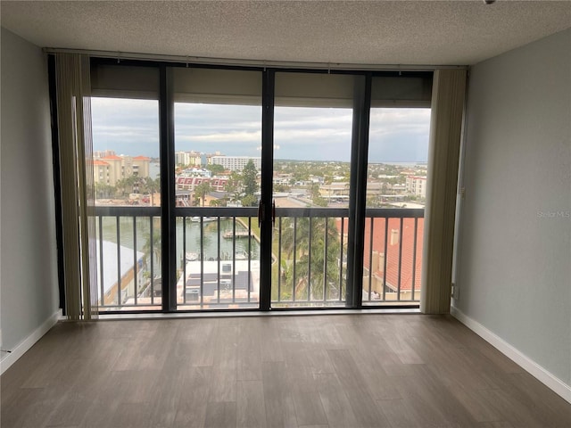 spare room with a water view, a healthy amount of sunlight, floor to ceiling windows, and a textured ceiling