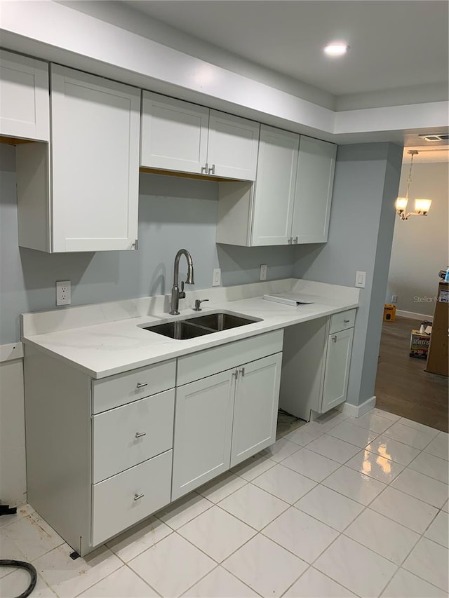 kitchen featuring light stone countertops, pendant lighting, an inviting chandelier, sink, and light tile patterned flooring