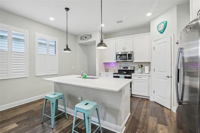 kitchen featuring white cabinetry, sink, decorative light fixtures, a kitchen bar, and appliances with stainless steel finishes