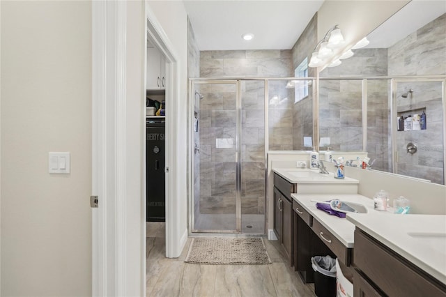 bathroom featuring a shower with door and vanity