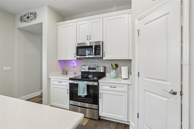 kitchen with light countertops, appliances with stainless steel finishes, dark wood-type flooring, white cabinetry, and baseboards