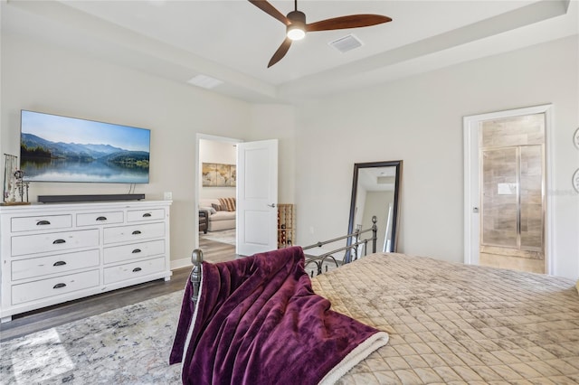 bedroom featuring dark wood-style flooring, a raised ceiling, visible vents, ensuite bathroom, and ceiling fan