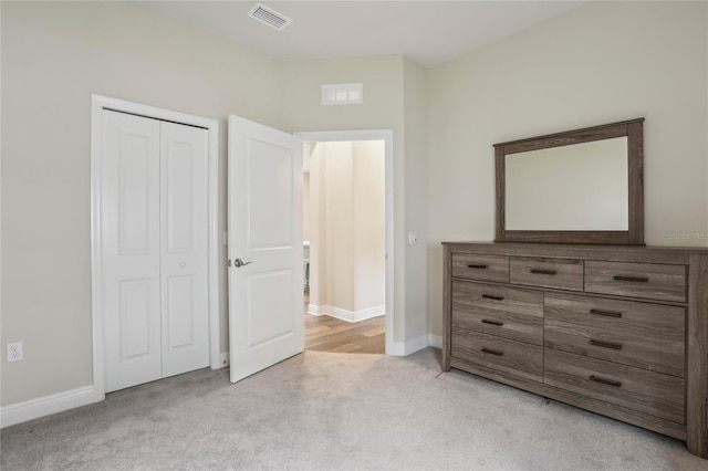 unfurnished bedroom with light colored carpet, a closet, visible vents, and baseboards