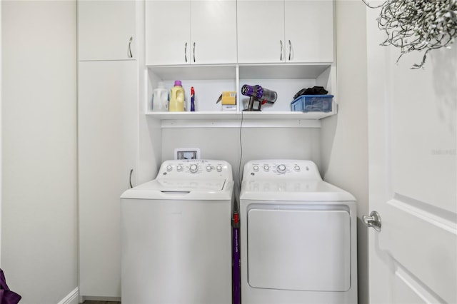 clothes washing area featuring washing machine and dryer and cabinet space