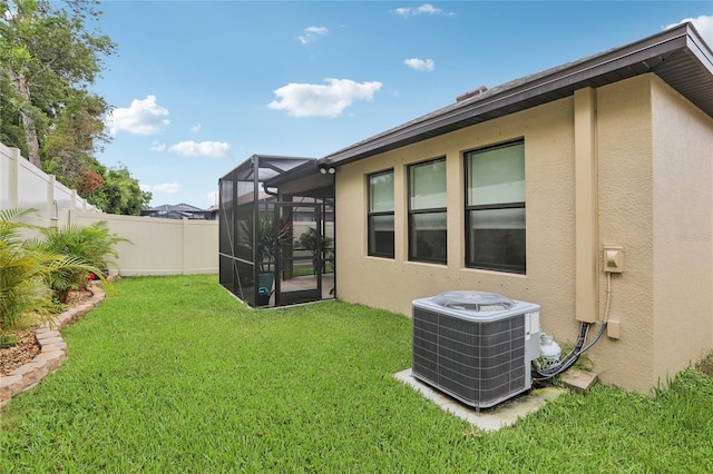 view of yard with central AC, a fenced backyard, and a lanai