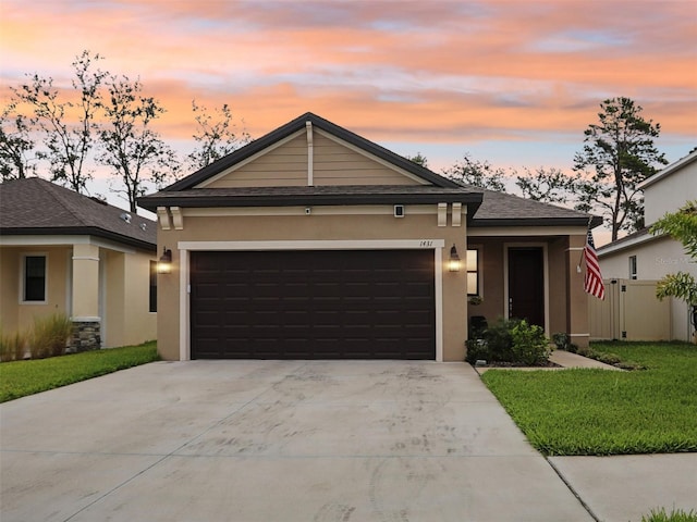 view of front facade with concrete driveway, a lawn, an attached garage, and stucco siding