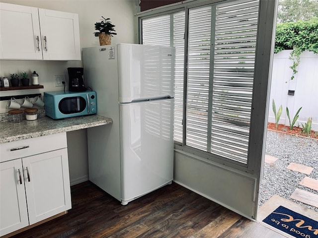 kitchen with white cabinetry, white fridge, and dark wood-type flooring