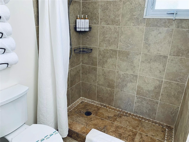 bathroom with a shower with shower curtain and toilet