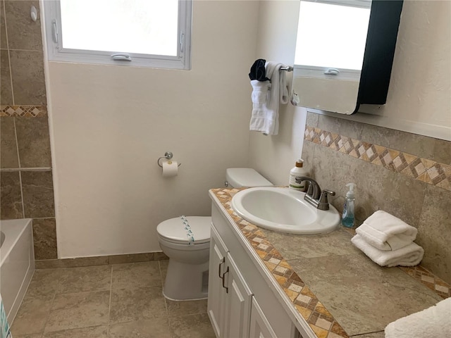 bathroom featuring tile patterned flooring, vanity, toilet, and a bathing tub