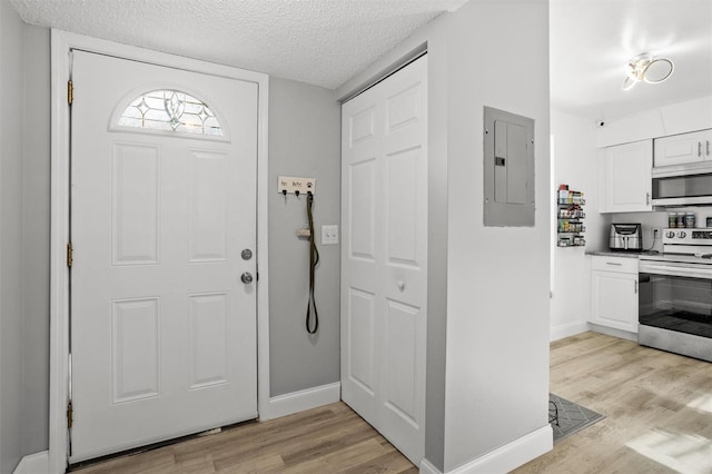 foyer with a textured ceiling, electric panel, and light hardwood / wood-style floors