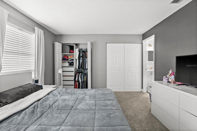 carpeted bedroom featuring a textured ceiling and two closets